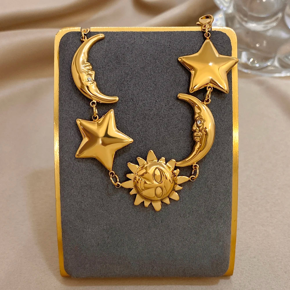 Gold-tone charm bracelet with star and crescent moon charms plus a sun centerpiece on chain