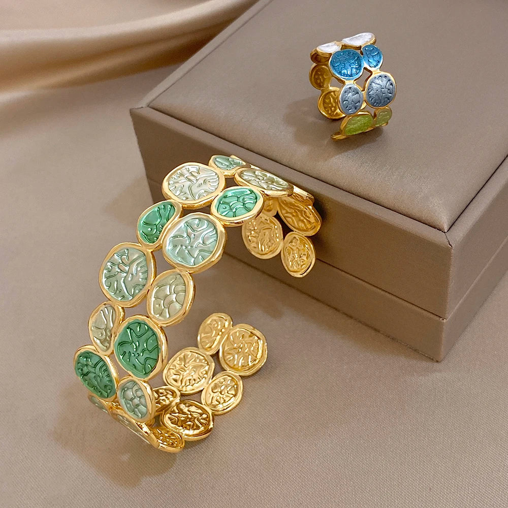 Gold-tone wide open cuff bracelet with green enamel leaf coin patchwork detail