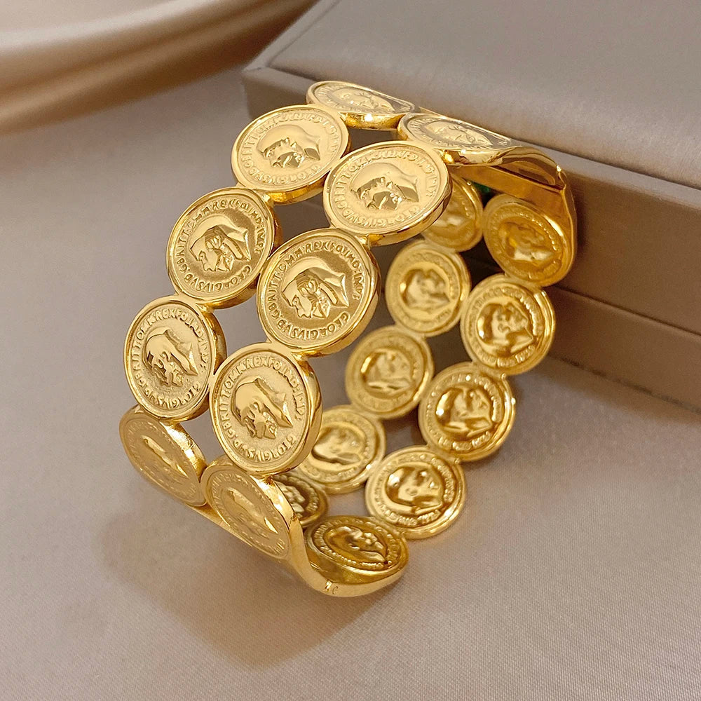 Gold plated coin cuff bangle with stacked round medallion discs and face motifs