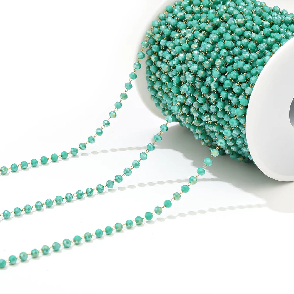 Turquoise faceted beaded chain on a white spool with dangling strands