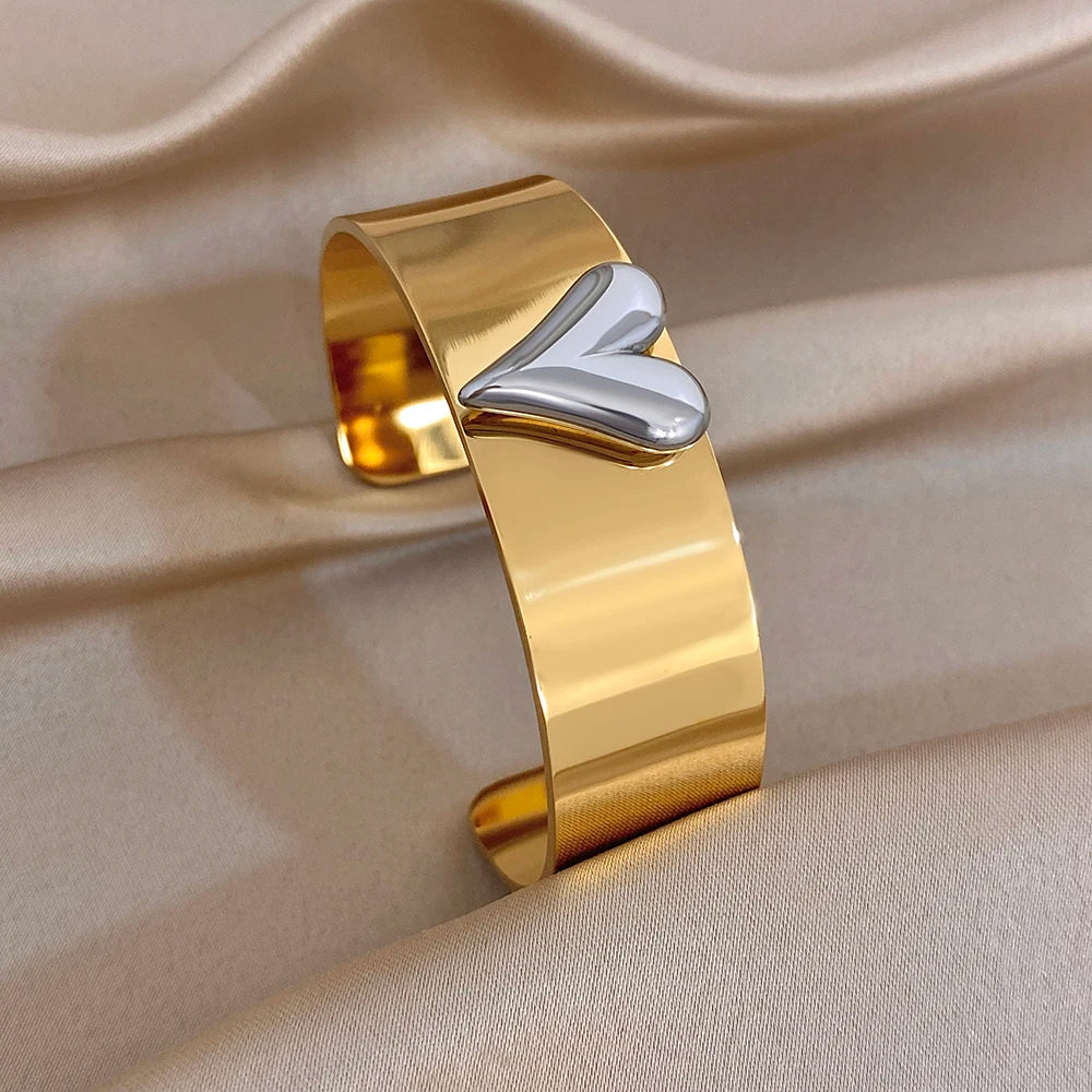 Gold glossy cuff bangle with raised heart detail and smooth wide band