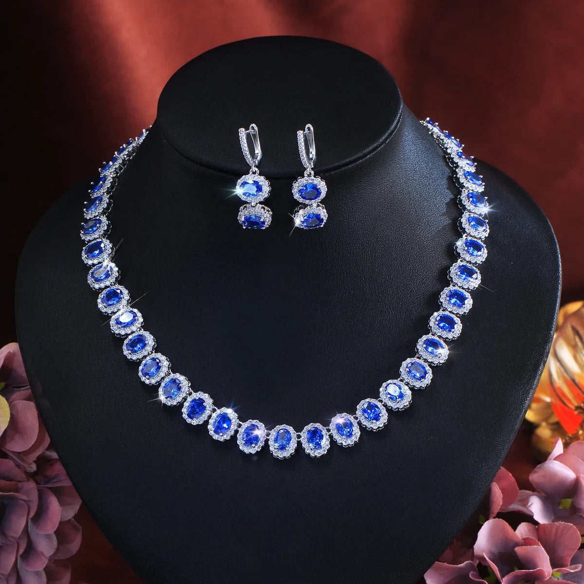 Royal blue cubic zirconia jewelry set on mannequin: drop hoop earrings and oval necklace