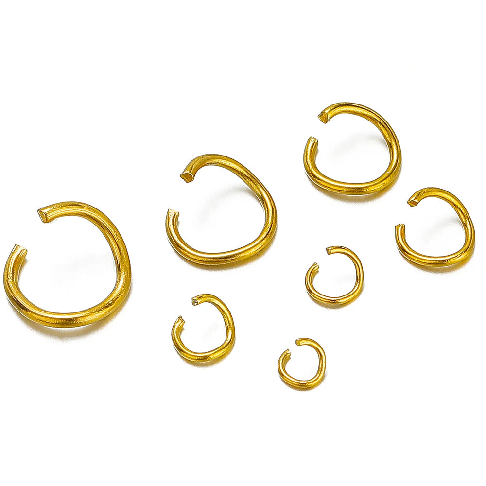 Gold-colored split rings and jump rings, scattered on a white background