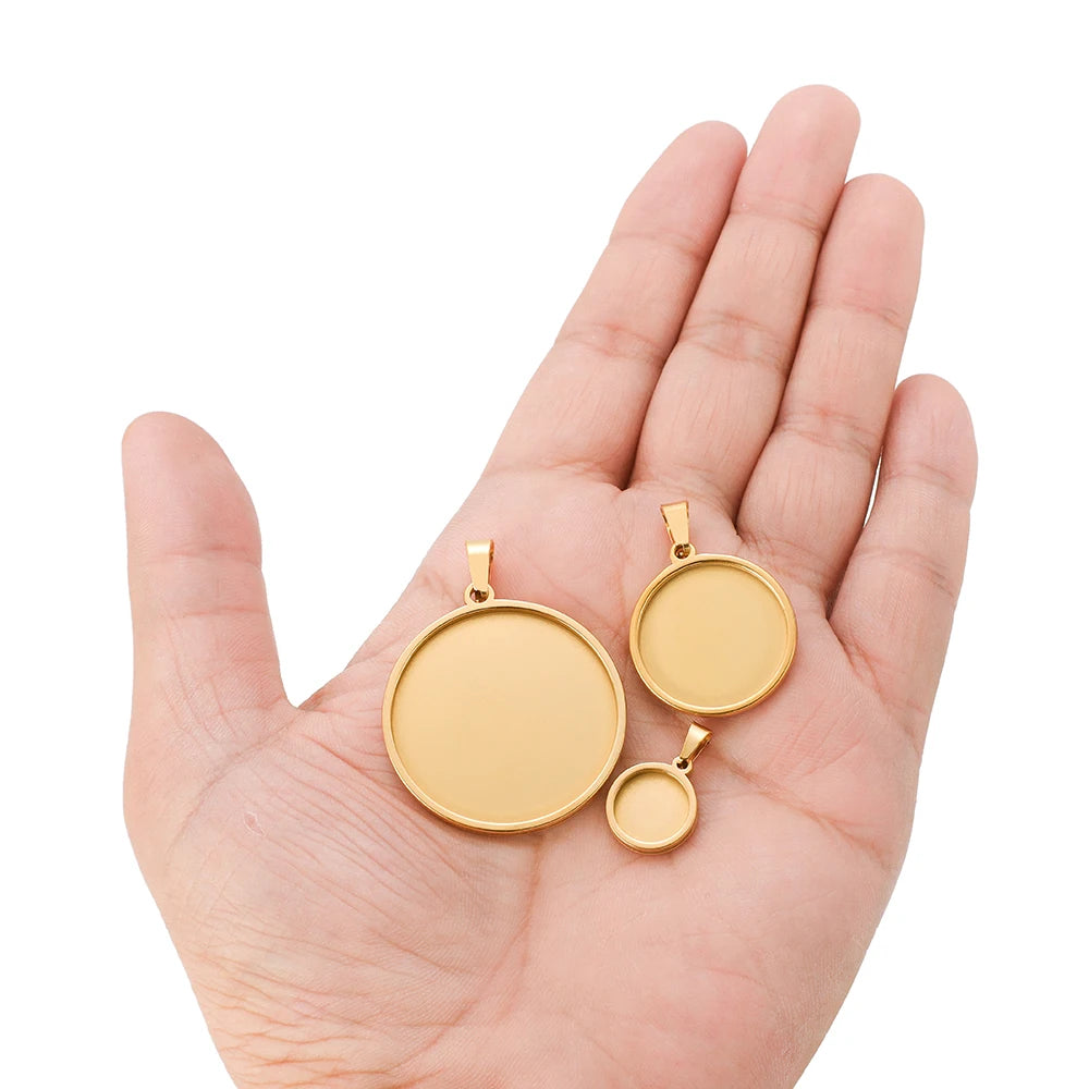 Gold-tone round cabochon bezel bases with clamp bails, held in a hand