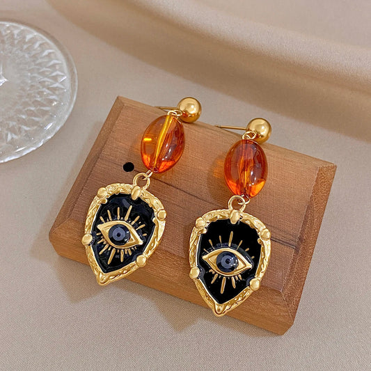 Gold-tone drop earrings with amber oval beads and blue evil-eye heart charms