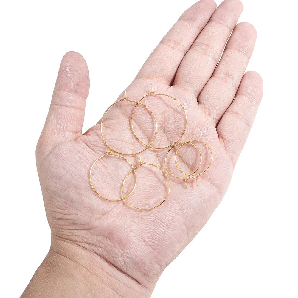 Gold hoop earring loops in hand, large round rings with small clasp tabs