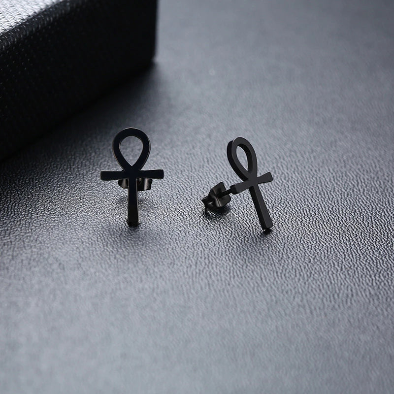 Black ankh cross stud earrings with visible post backs, pair on surface