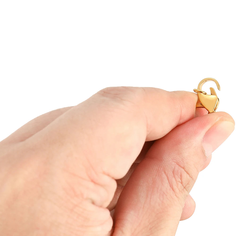 Gold lobster clasp with jump ring, held in hand close-up