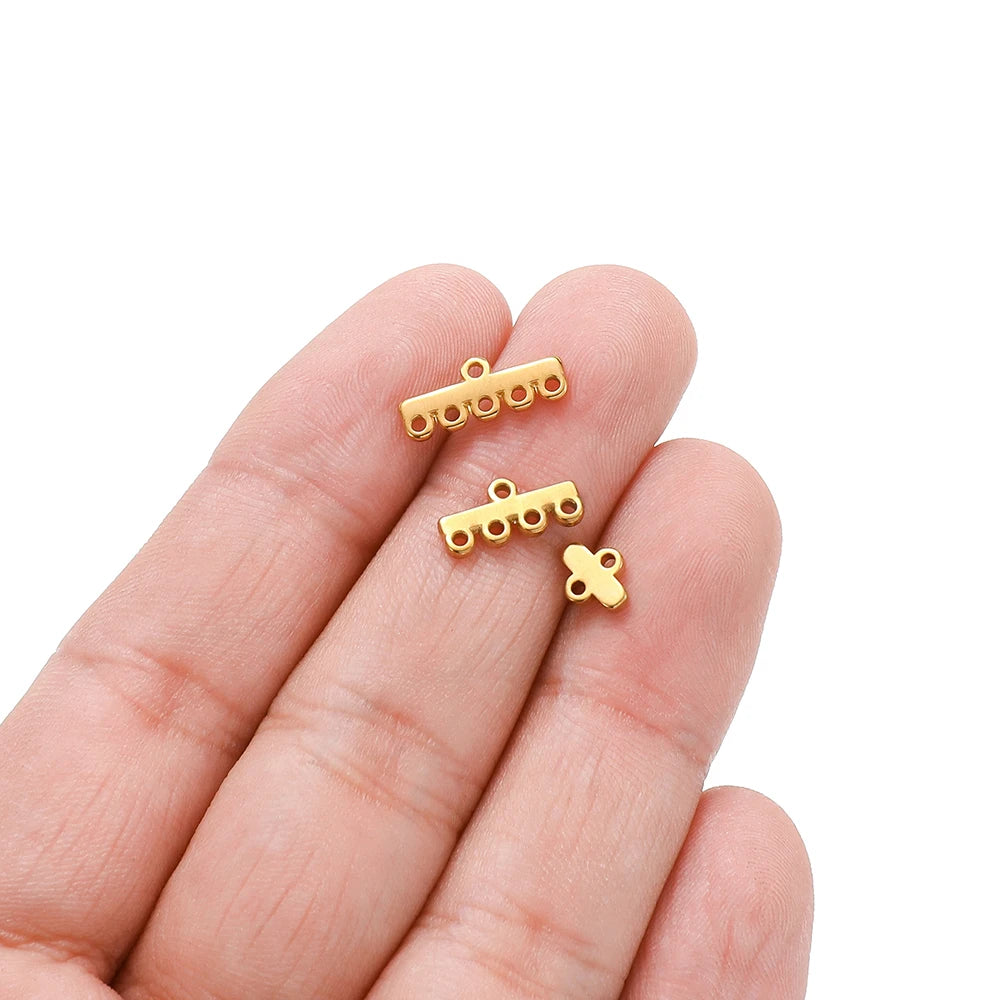 Gold-toned clasp bail connectors held in hand: small bar and cross link pieces