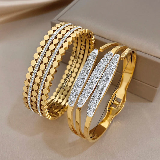Gold-tone wide cuff bangle with textured geometric links and clear rhinestone bands