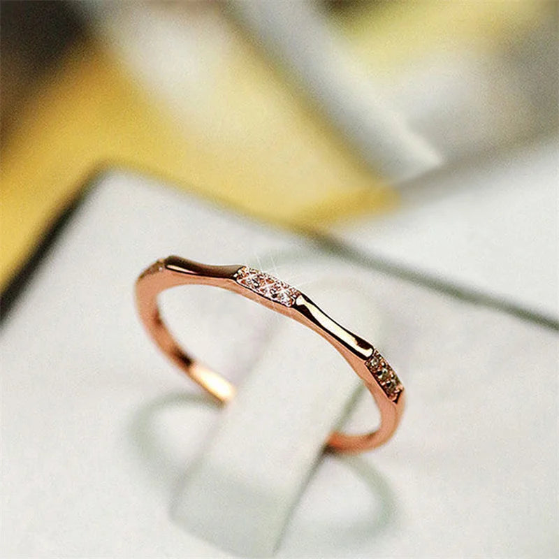 Minimalist cubic zirconia wedding ring, rose-gold tone band with central stone sparkle