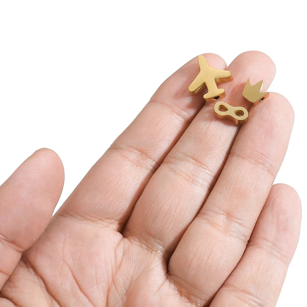 Gold-tone stainless steel spacer beads on fingers, assorted animal and symbol shapes