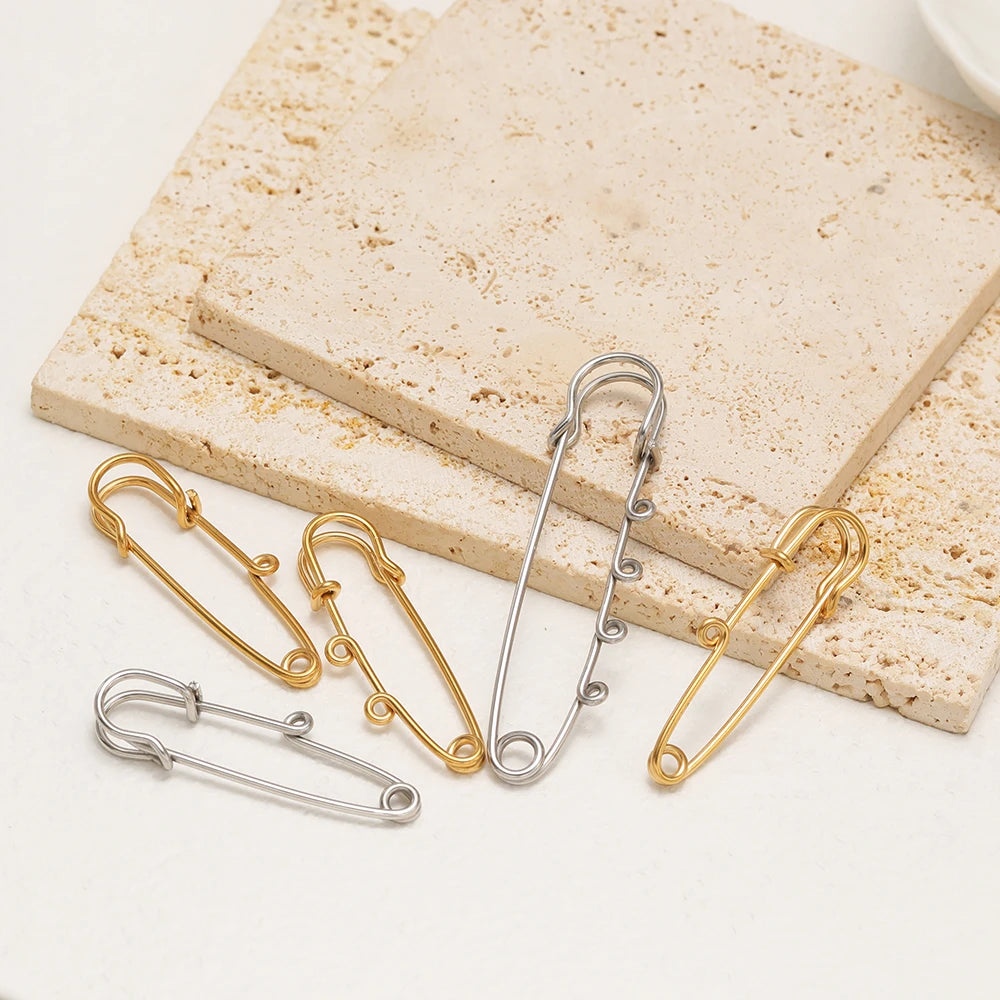 Silver and gold multi-hole safety pin brooch fasteners, lying on display