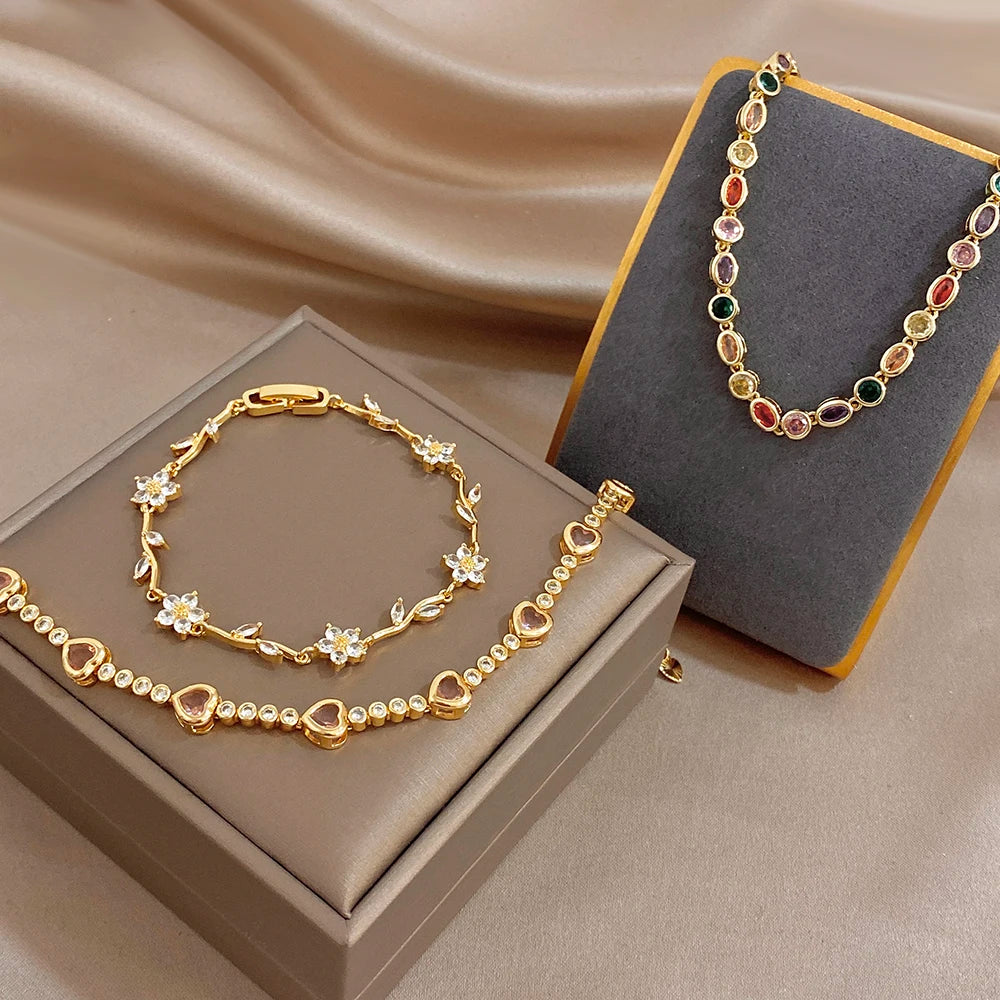 Set of three gold-tone chain bracelets with rainbow zircon beads and flower charms