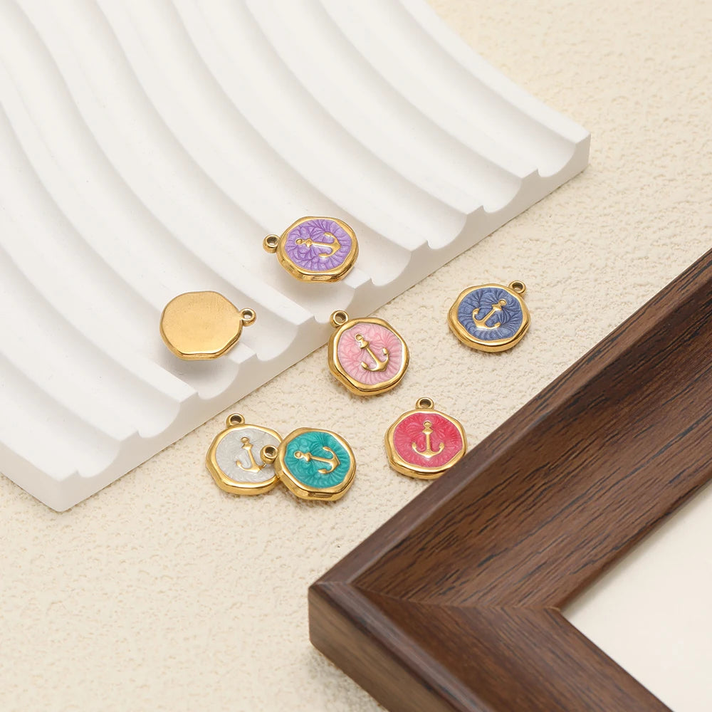 Small enamel charm pendants with anchor and paw icons, each with gold-tone bail