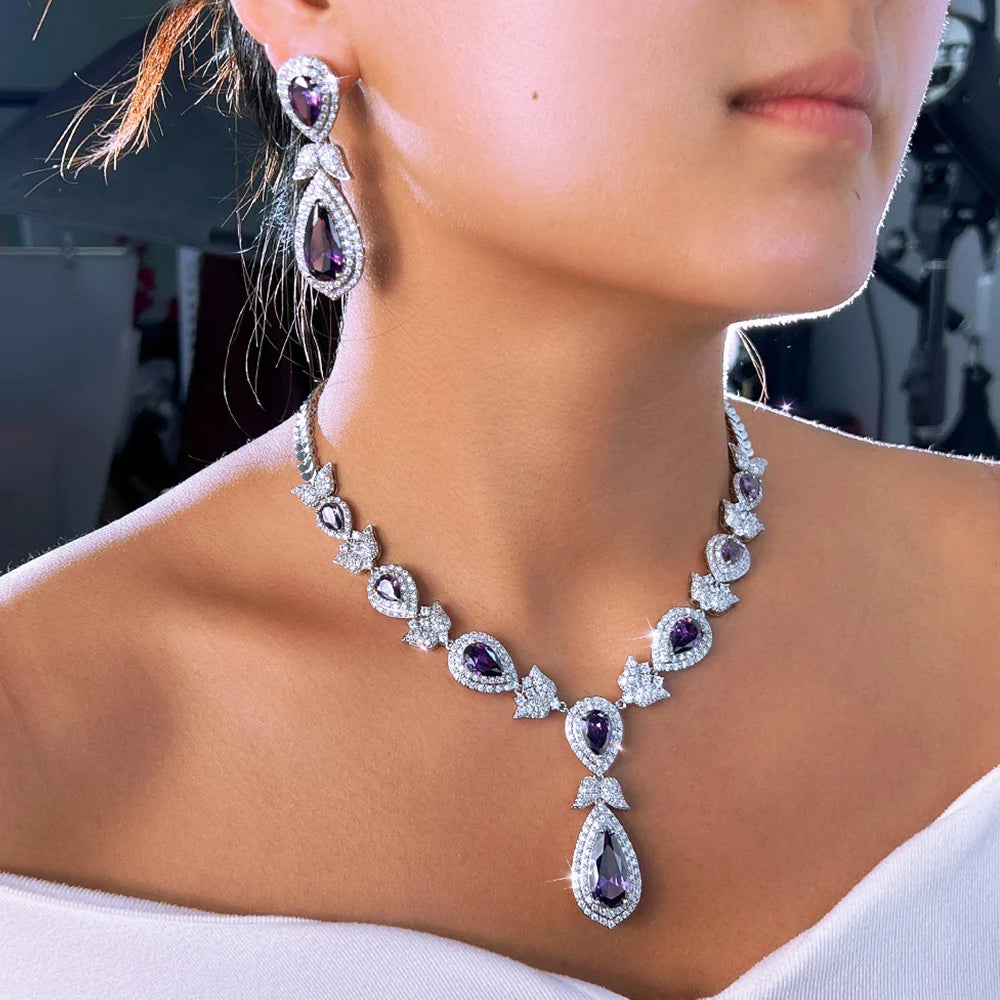 Purple crystal necklace and drop earring worn, showing the teardrop pendant and bow details