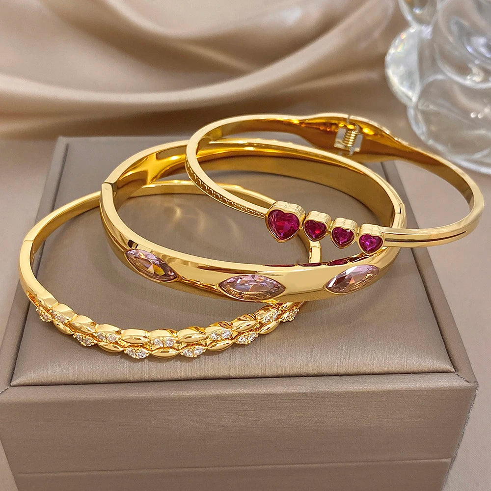 Gold tone stackable bangles with purple and pink zircon accents and heart detail