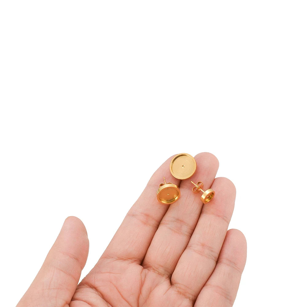 Gold-tone round stud earring blank bases with posts shown in an open hand
