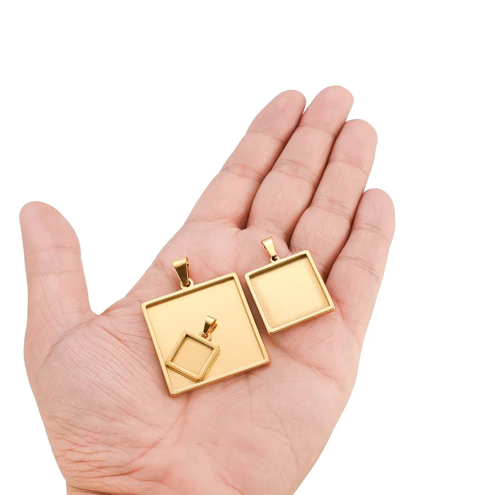 Square gold pendant tray bezels with bail, held in hand, cabochon blank charms set