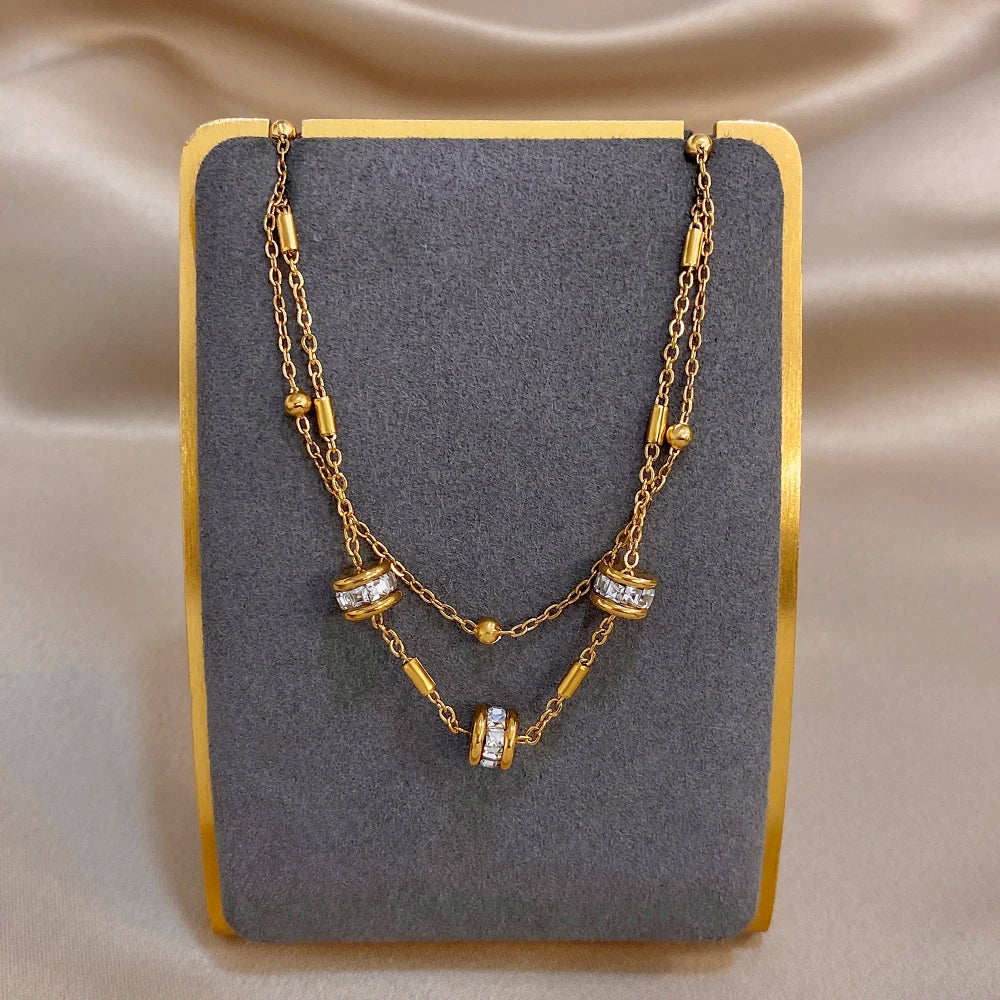 Gold double-layer chain bracelet with cylindrical rhinestone bead charms and clasp.