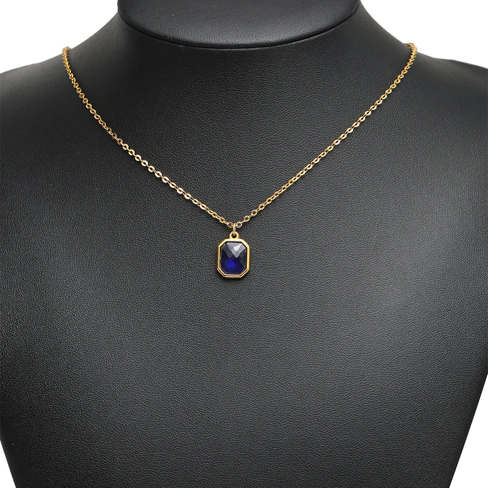 Blue faceted glass charm pendant with gold-tone loop on a gold-tone chain