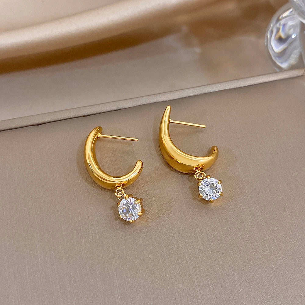 Gold-tone hoop earrings with dangling clear round crystals, side view