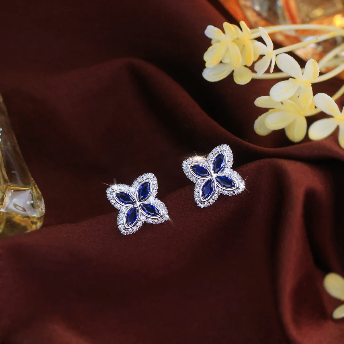 Pair of four-leaf stud earrings with deep blue stones and clear accents