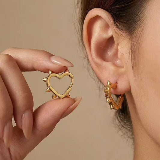 Gold heart hoop earrings with studded spikes around the heart center
