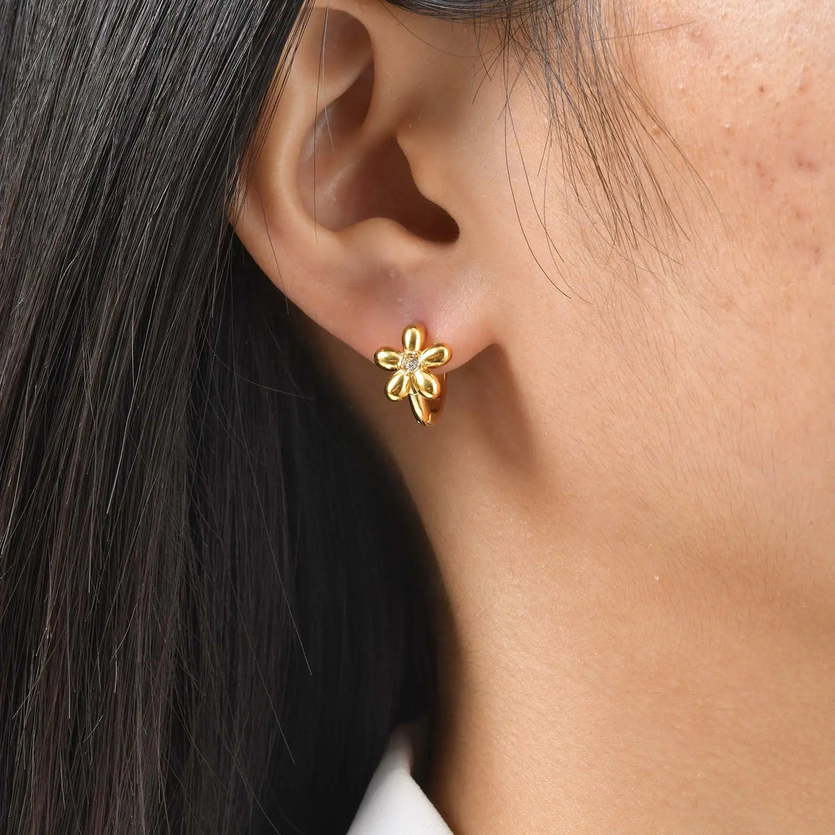 Gold-tone cubic zirconia clover flower huggie hoop earrings on ear