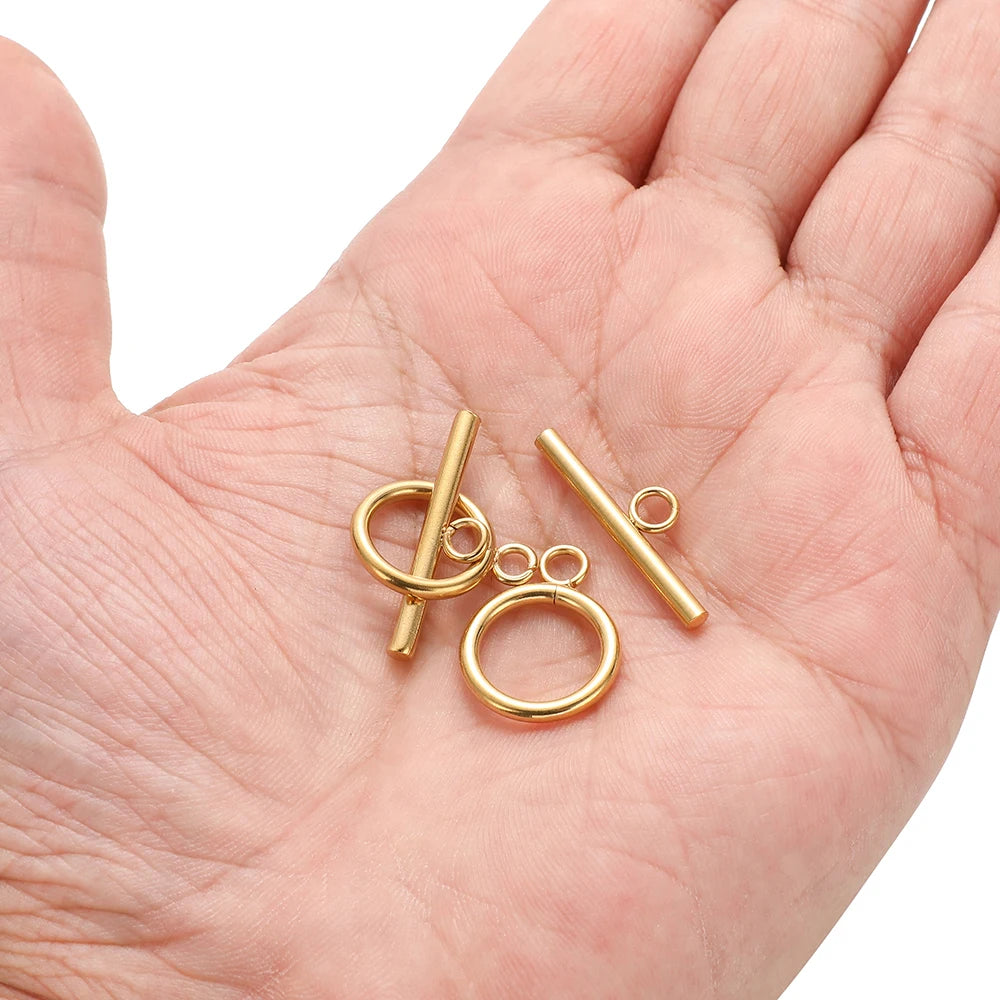 Gold-tone OT clasp connectors in hand: ring loops and straight bar pieces