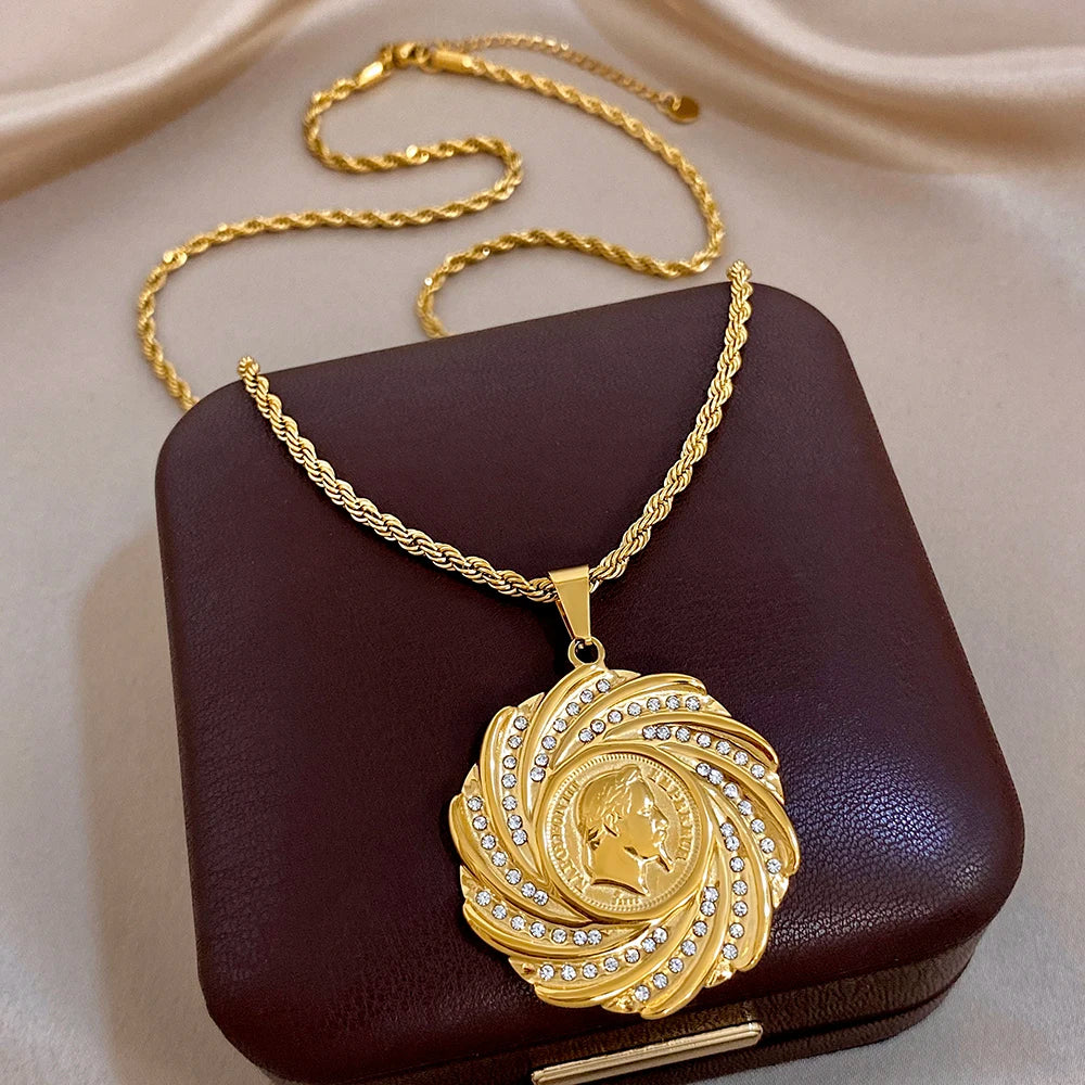 Gold-tone swirl coin pendant necklace with rhinestone accents and lion profile