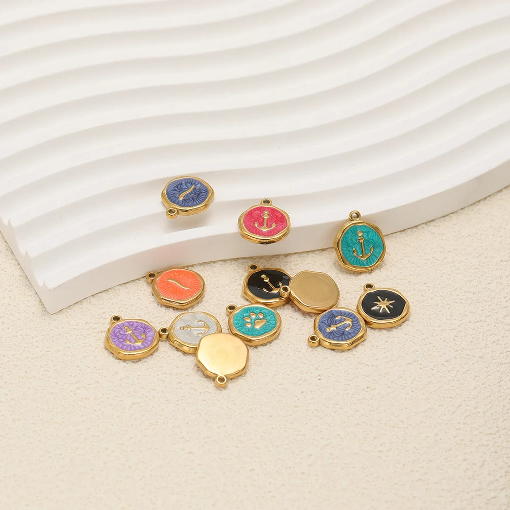 Assorted enamel charm pendants with anchor and star icons in mixed colors, gold loops