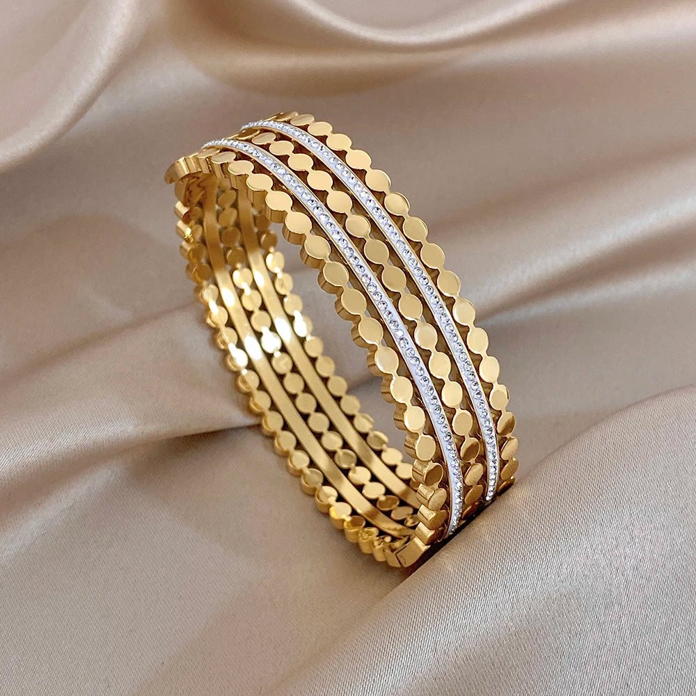 Gold-tone wide cuff bangle with layered beaded bands and blue-toned crystal stripe
