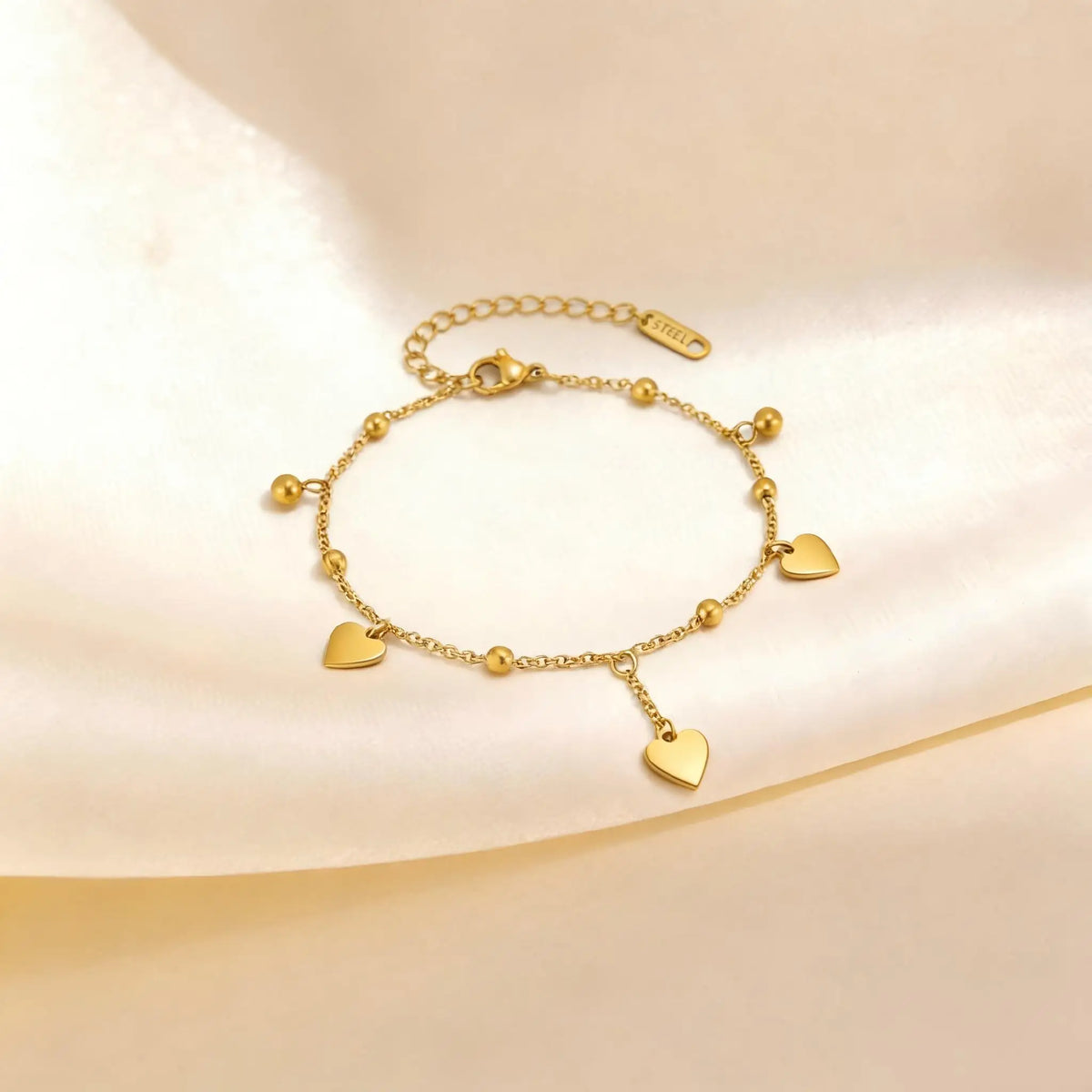 Gold heart anklet with beaded chain, multiple heart charms, and adjustable clasp