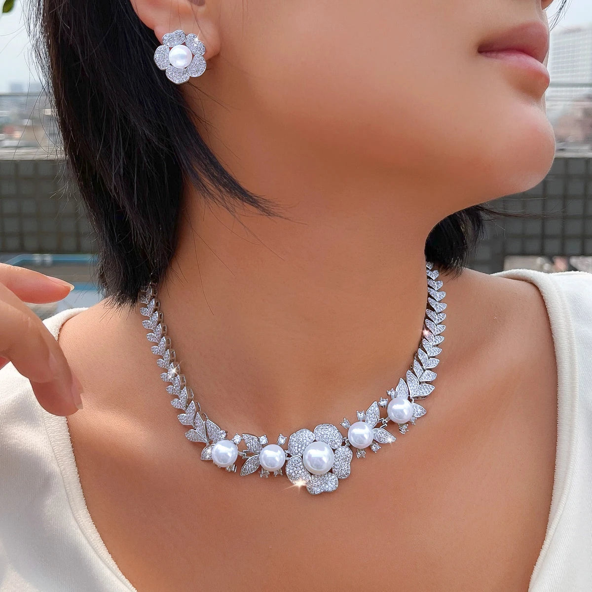 Silver-tone pearl and cubic zirconia necklace with matching flower earring, worn