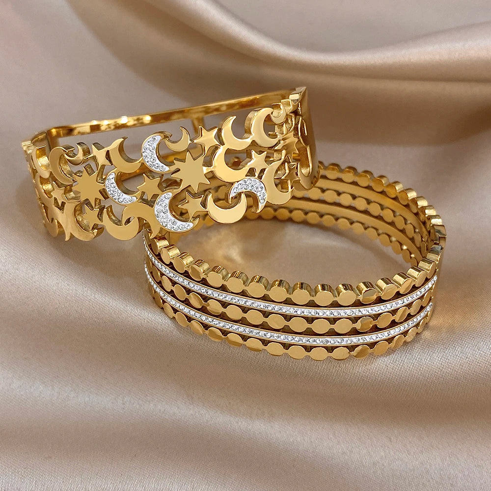 Two gold-tone wide cuff bangles with crystal-lined stripes and star-moon cutout design