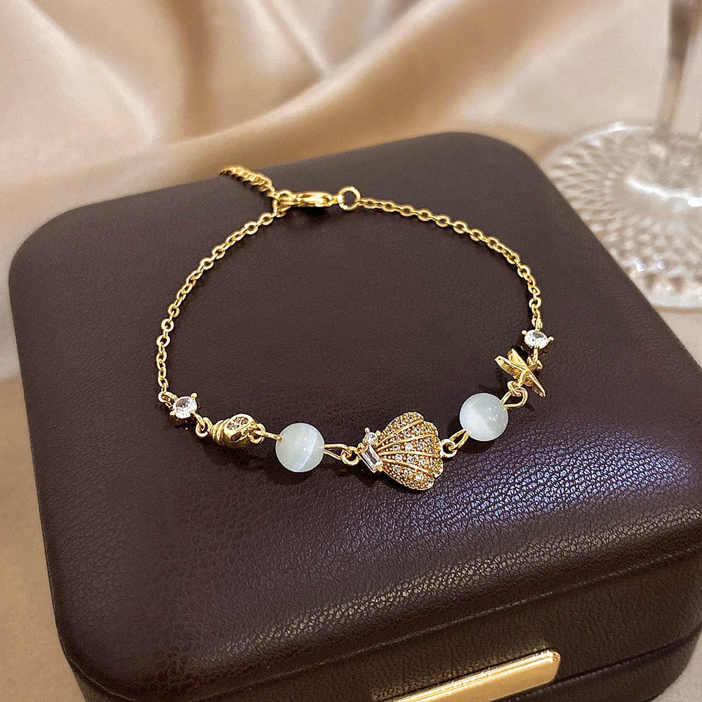Gold-tone charm bracelet with starfish, shell, moonstone-style beads and rhinestone details
