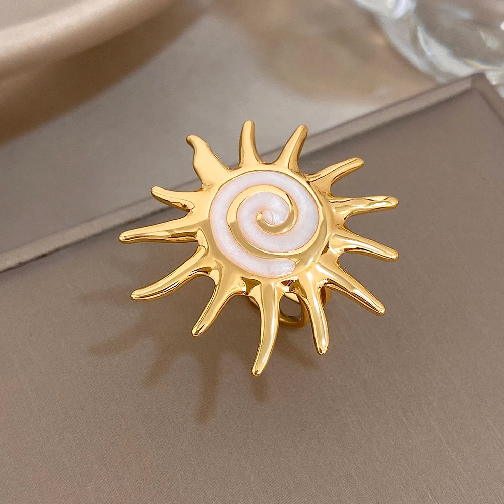 Gold-plated sunburst ring with pale lavender spiral enamel center, close-up