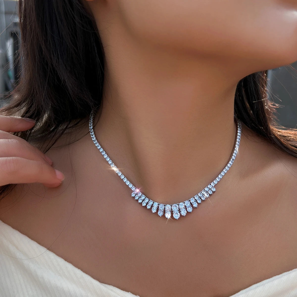 Cubic zirconia necklace worn at the neckline, with teardrop stones along the front