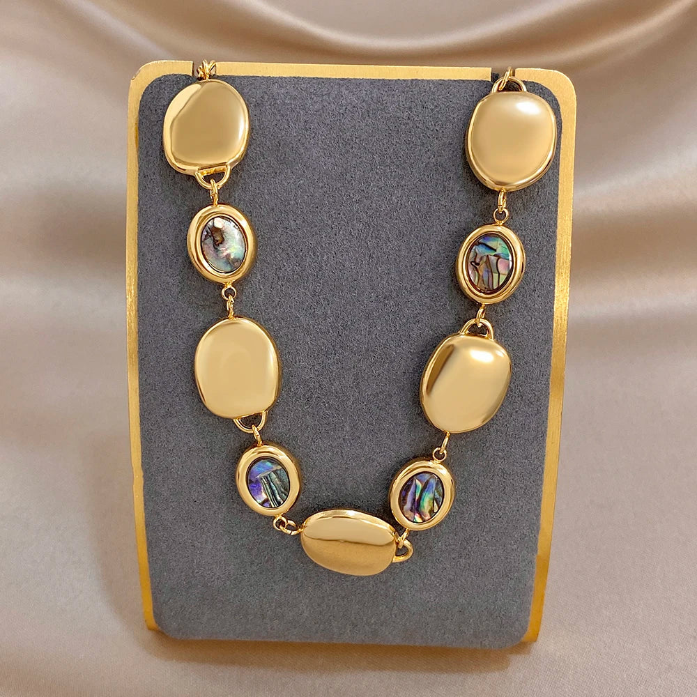 Gold-tone chain bracelet with alternating oval discs and iridescent abalone shell bead accents