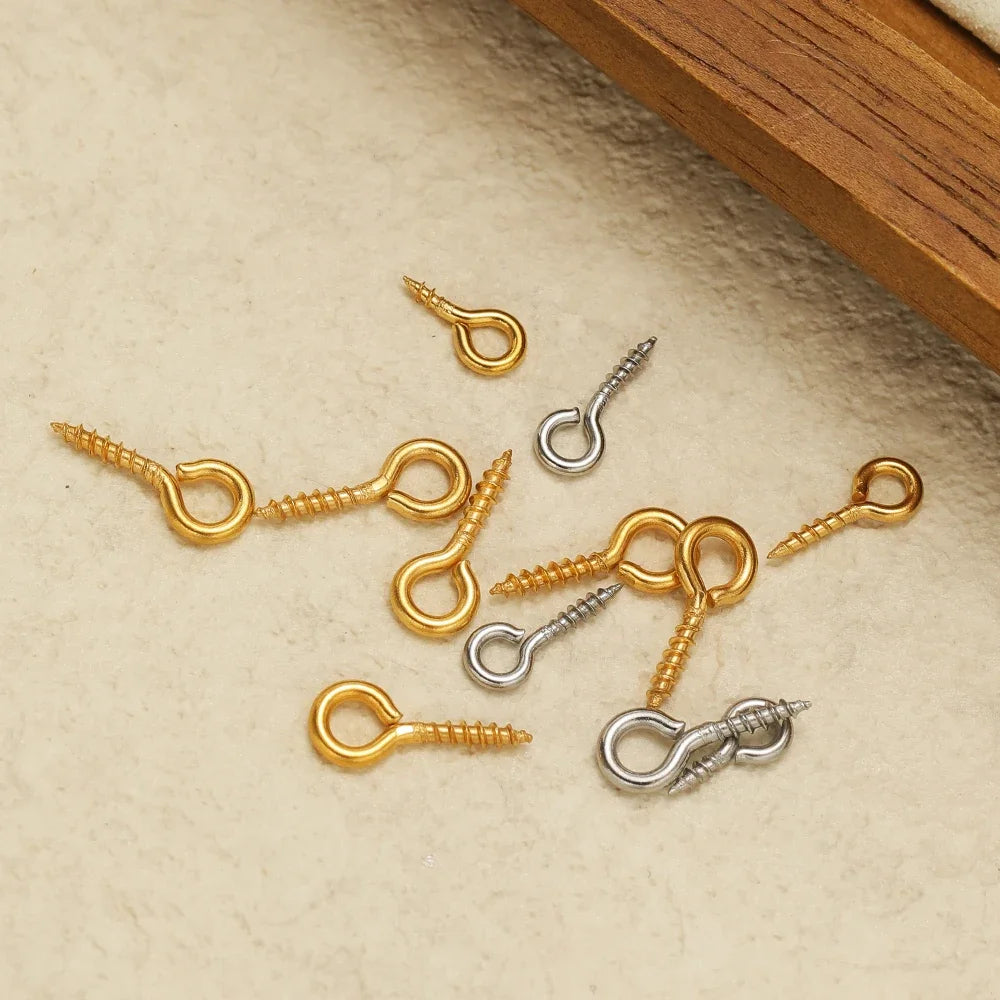 Assorted gold and silver screw eye pins with threaded shafts and looped eye hooks
