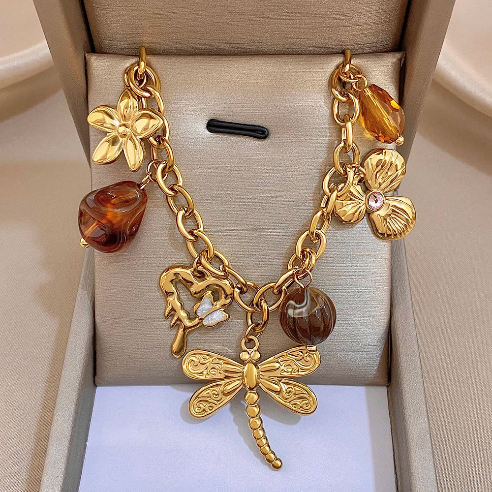 Gold chain necklace with amber heart charm, bow pendant, and orange drop charms