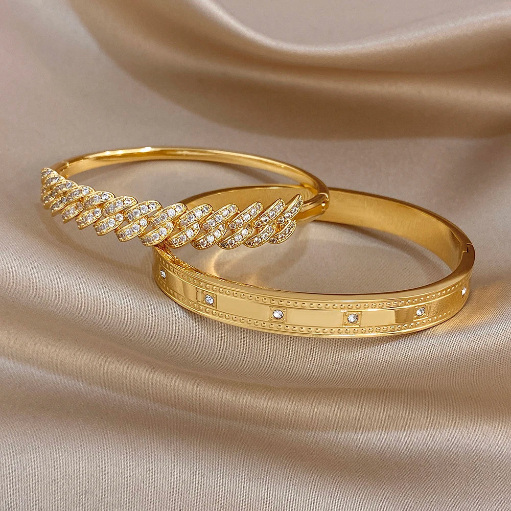 Gold tone cuff bracelets: one with clear rhinestone link cluster, one with dot inset trim.