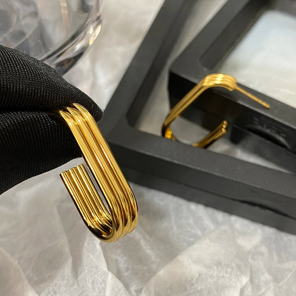 Gold-tone ridged hoop earring held up, showing its open U-shaped design