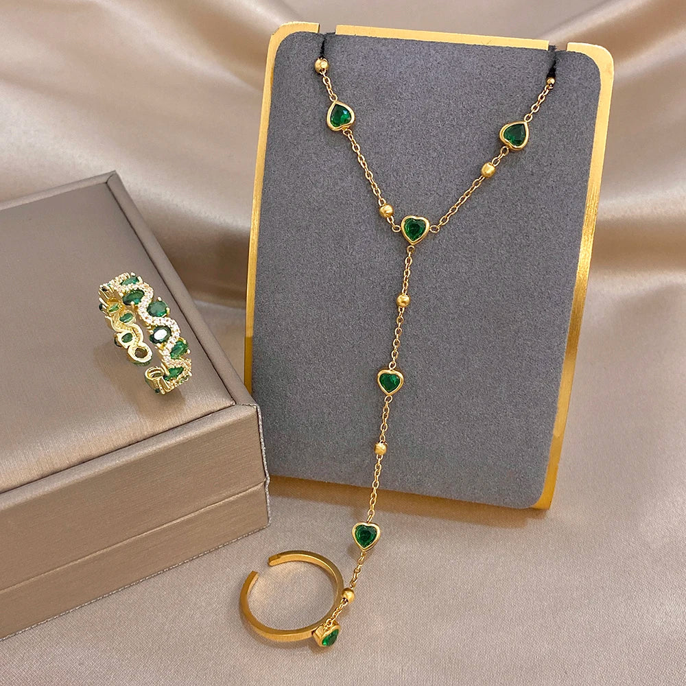 Gold-plated jewelry set with green heart bead chain bracelet and rings on display