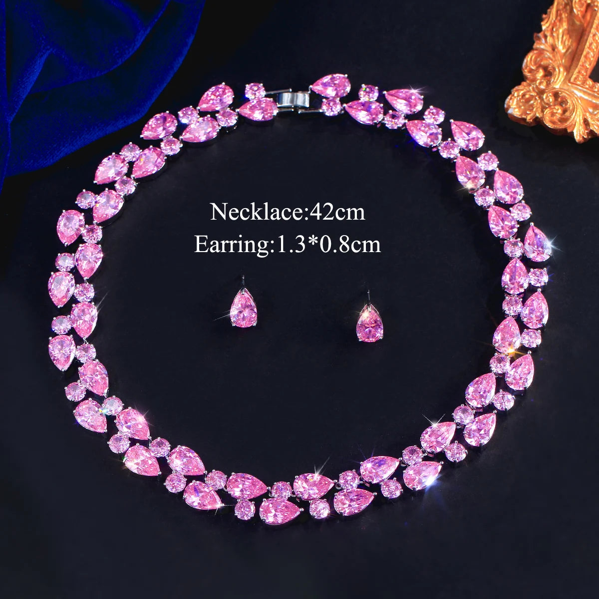 Pink rhinestone teardrop necklace with matching drop earrings on dark display