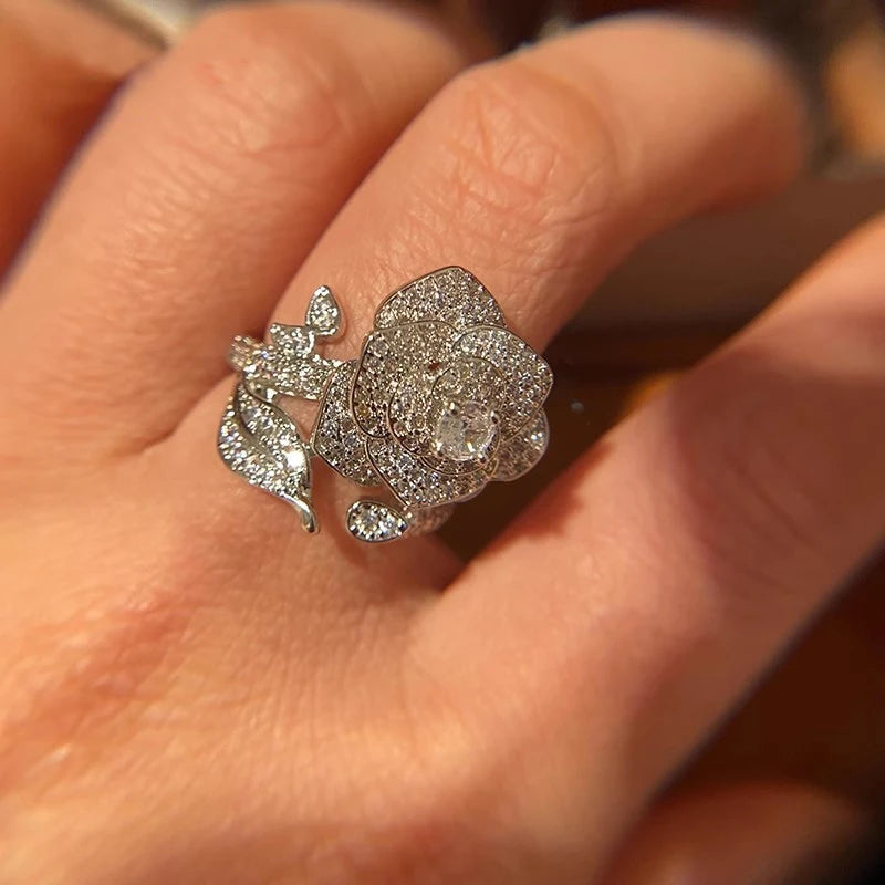 Silver-tone open band ring with large flower face and small teardrop zirconia accents.
