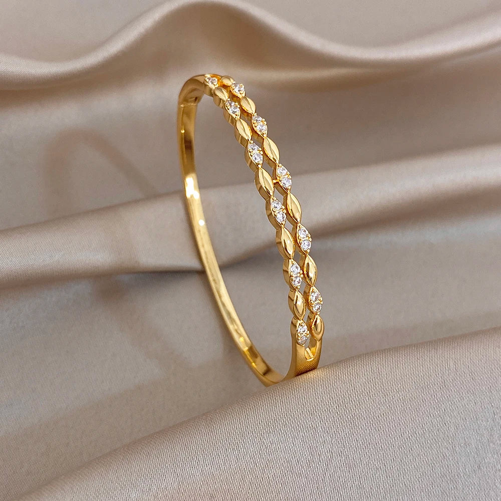 Gold tone hinged bangle with pink and clear zircon oval stones, slim cuff