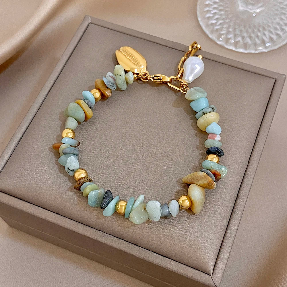 Beaded charm bracelet with gold chain, irregular stones in light blue and cream, seashell pearl