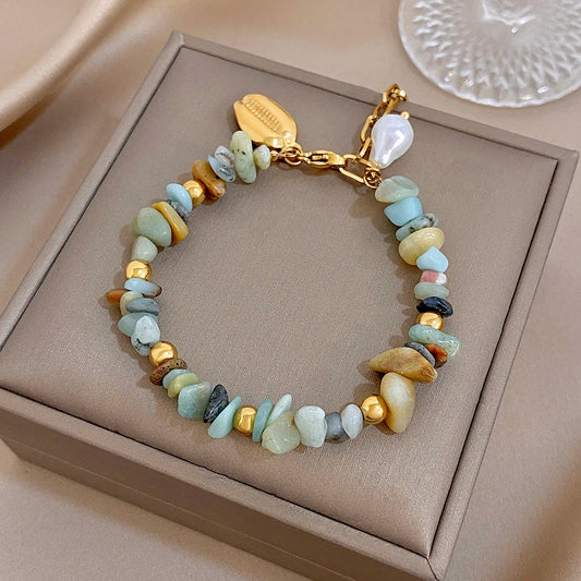 Beaded charm bracelet with gold chain, irregular stones in light blue and cream, seashell pearl